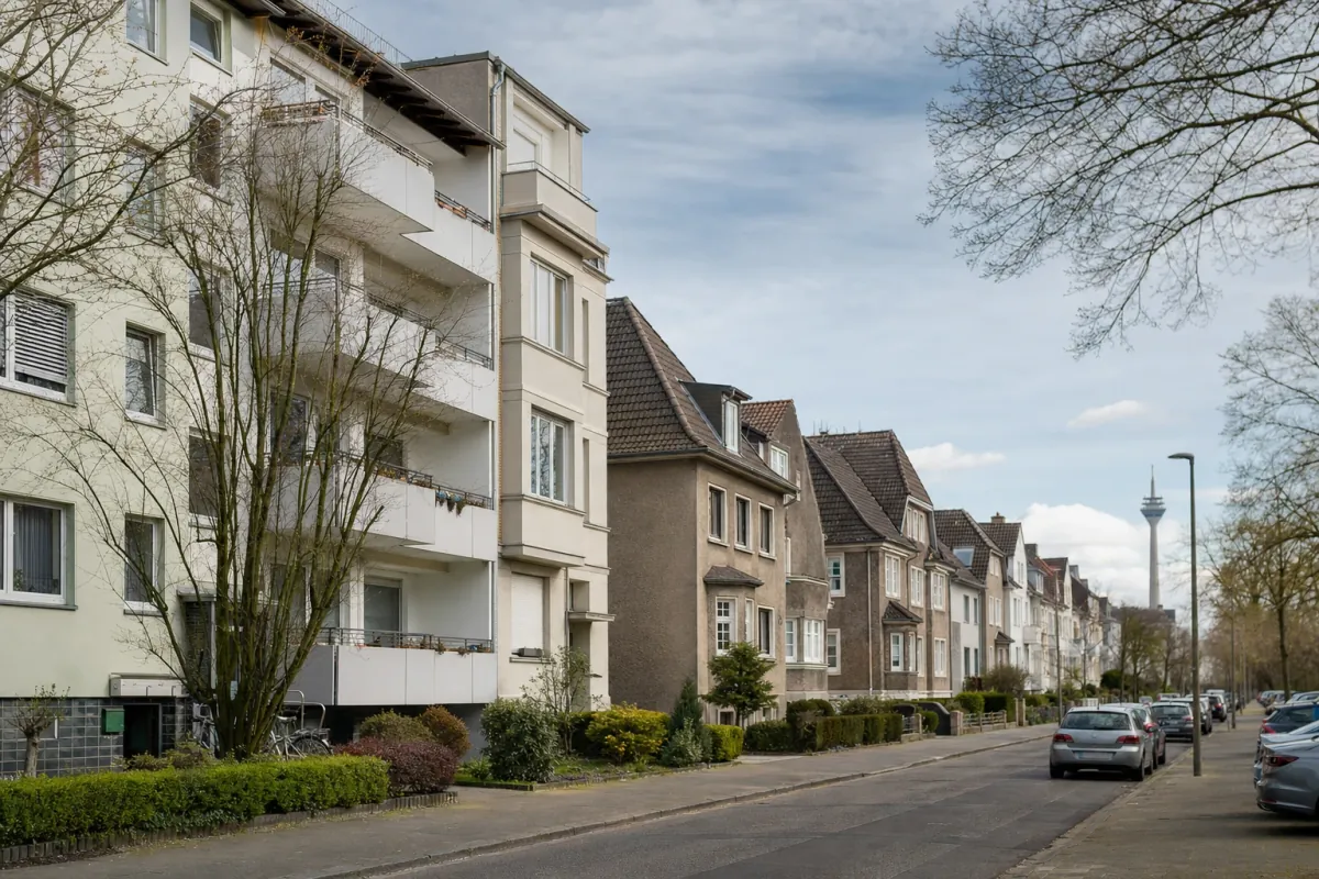 Wohnstraße in Düsseldorf: die für die Stadt typische Bebauung, im Hintergrund über den Dächern ein Wahrzeichen der Stadt.