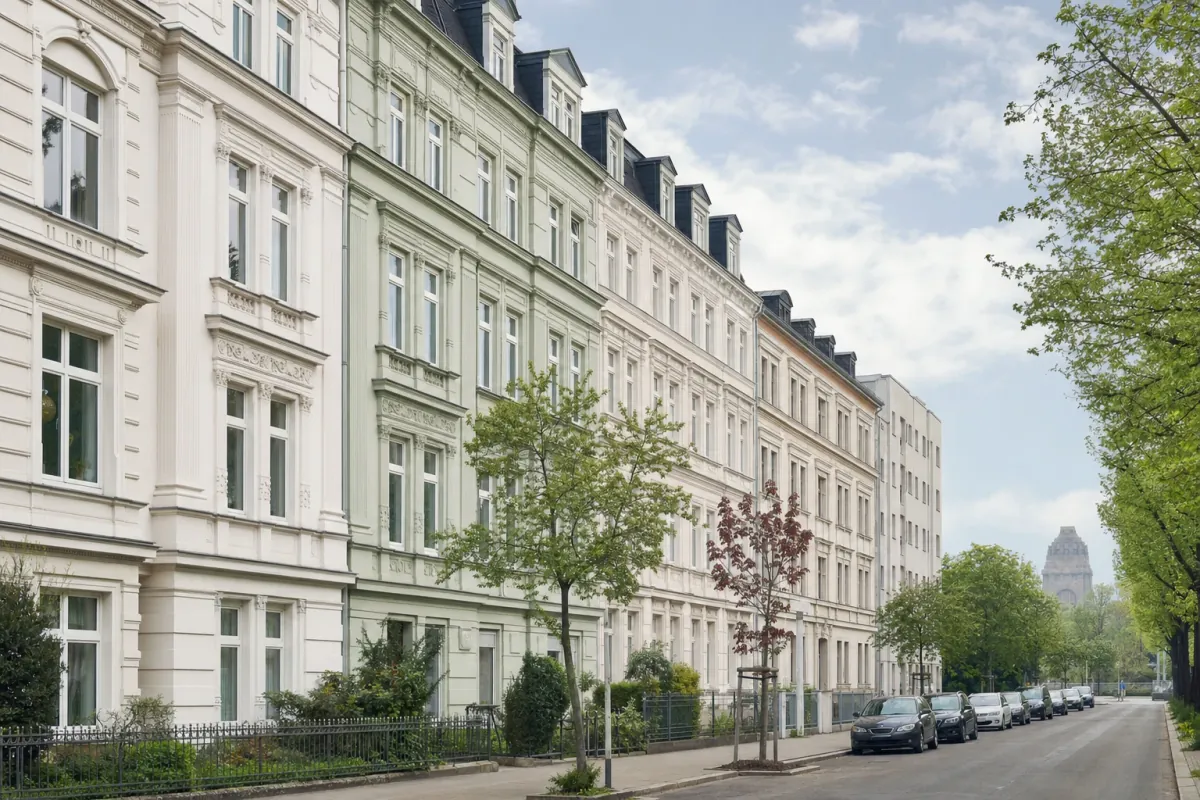 Wohnstraße in Leipzig: die für die Stadt typische Bebauung, im Hintergrund über den Dächern ein Wahrzeichen der Stadt.